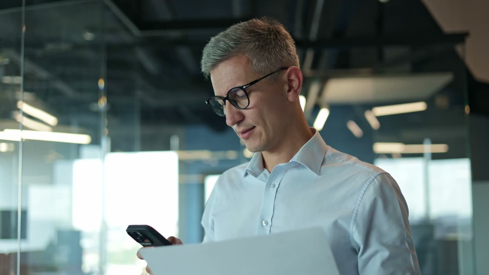 Policyholder reviewing a carrier estimate against paperwork while checking figures on a phone