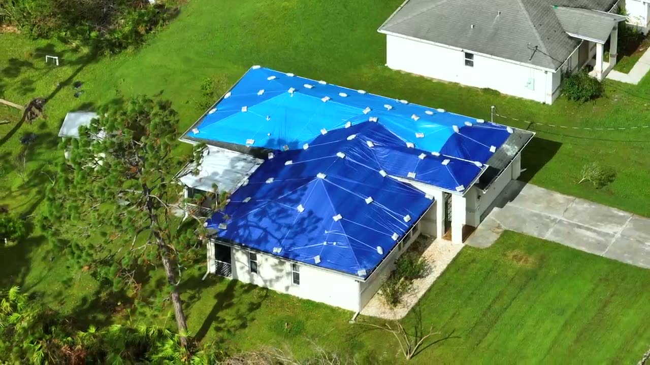 A storm-damaged roof still under a blue tarp months after the loss, the damage behind a denied Milton, FL roof damage insurance claim