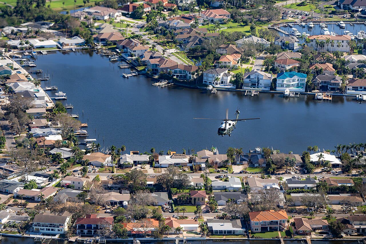 Aerial view of St. Petersburg-area canal neighborhoods during the October 13 presidential damage survey, debris piles line the streets